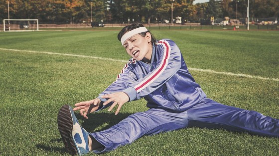 Woman in a tracksuit on a soccer field stretching