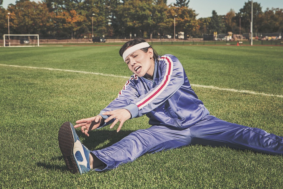 Woman in a tracksuit on a soccer field stretching