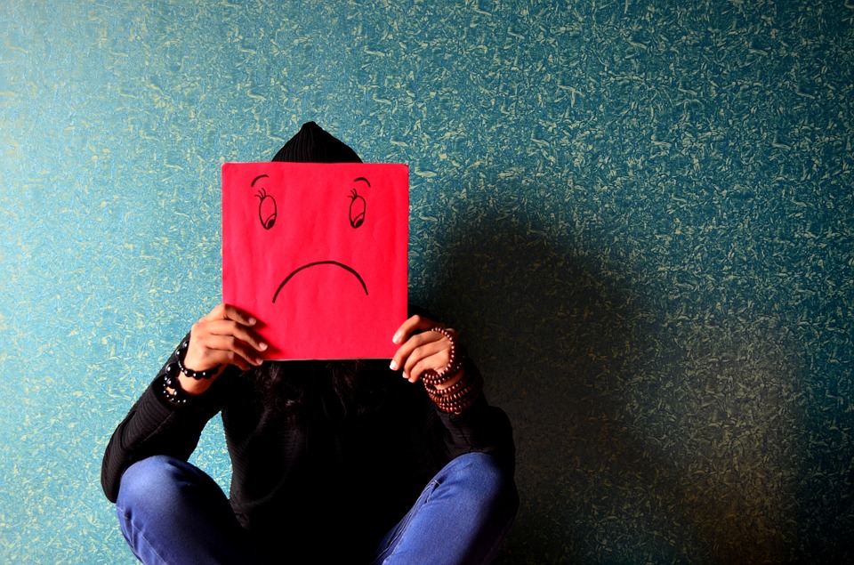 Person with a board over their face showing an unhappy face