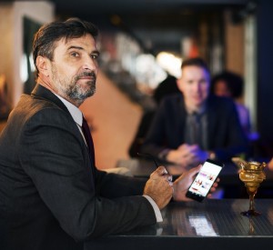 man on his phone at a bar looking very senior work figure