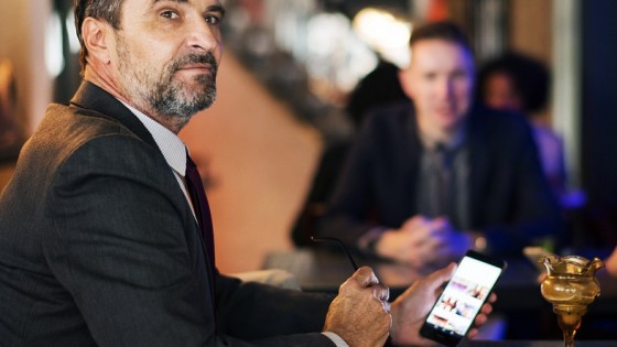 man on his phone at a bar looking very senior work figure