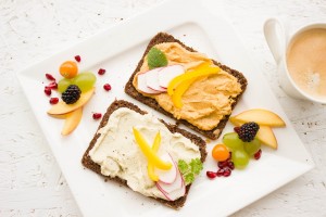 Fruit on toast with a variety of different healthy looking spreads and extra fruit on the outside of the plate
