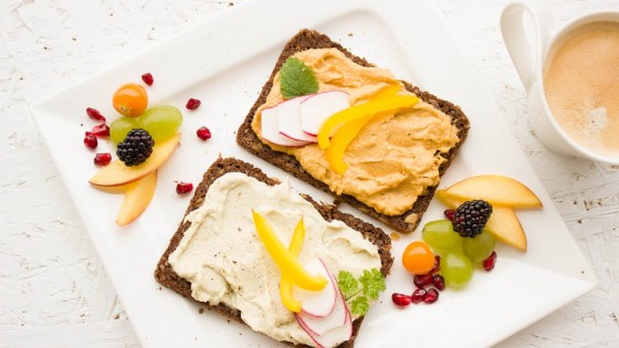 Fruit on toast with a variety of different healthy looking spreads and extra fruit on the outside of the plate