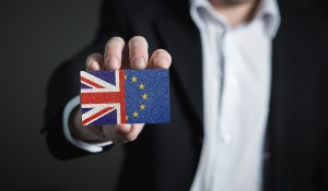 Businessman in a suit holding a business card held Union Jack half EU flag