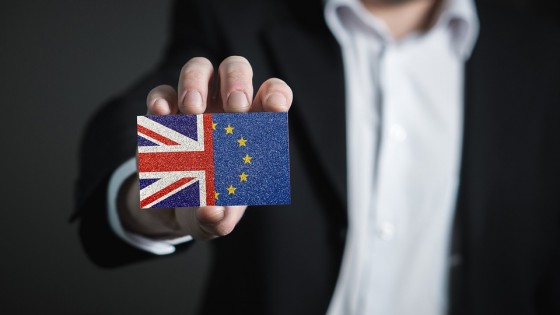 Businessman in a suit holding a business card held Union Jack half EU flag