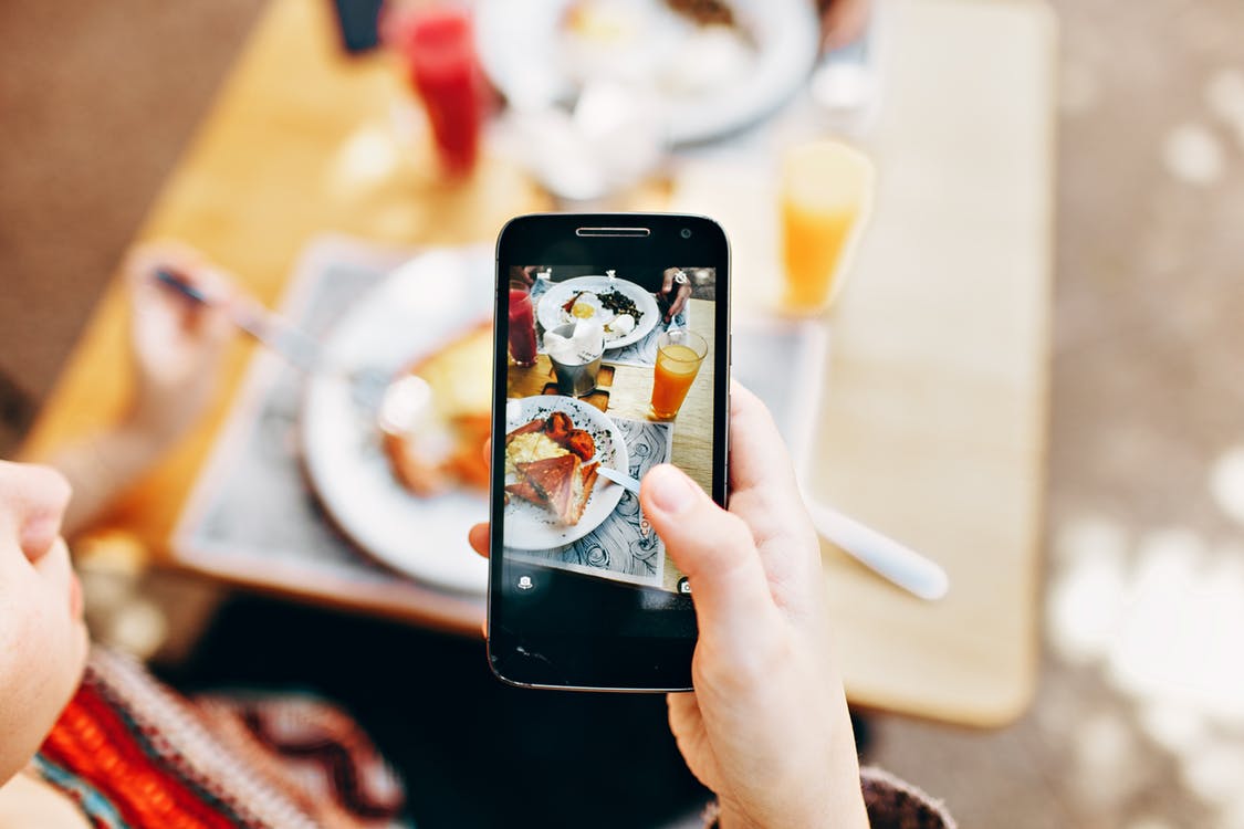 smartphone taking a photo of a breakfast meal with orange juice