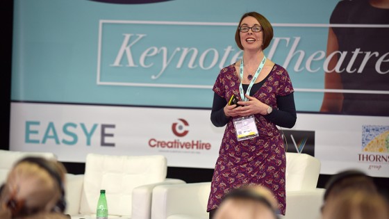 Woman stood up as a speaker in front of a masterclass of people