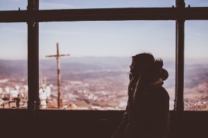 A girl looking out a window over a city to show personal reflection