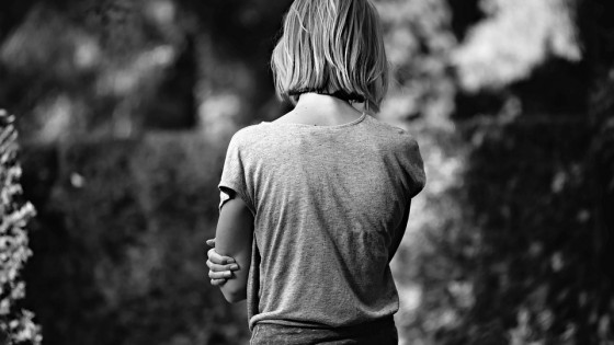 Woman standing along in black and white, back to camera