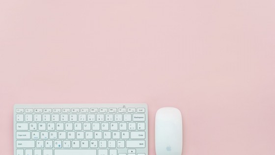 A keyboard and mouse on a plain pink background