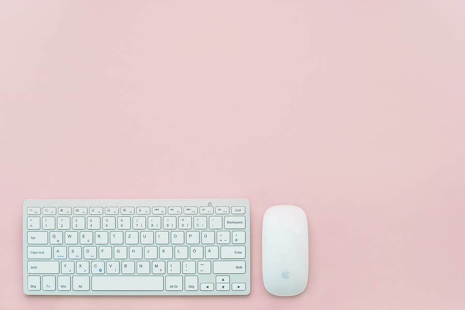 A keyboard and mouse on a plain pink background